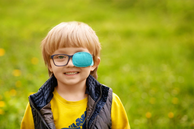Na foto uma criança usando tampão (oclusão) no olho esquerdo